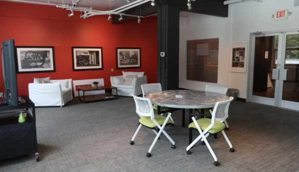 Interior Denison Edge Room with red wall, table with chairs, and soft seating.