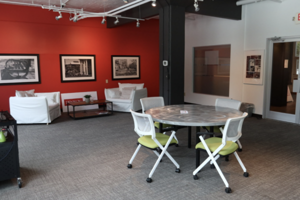 Interior Denison Edge Room with red wall, table with chairs, and soft seating.